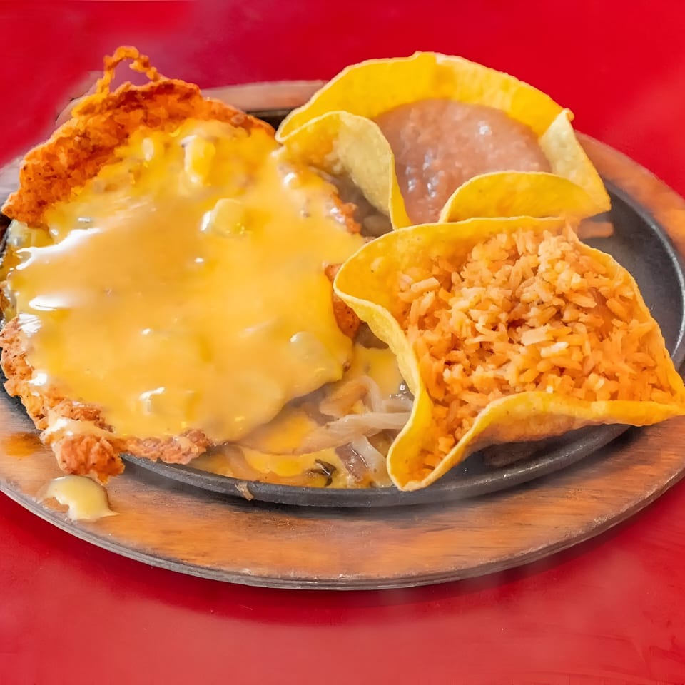 Julio's Mexican Restaurant's sizzling platter with a cheese-covered dish, rice, and refried beans.