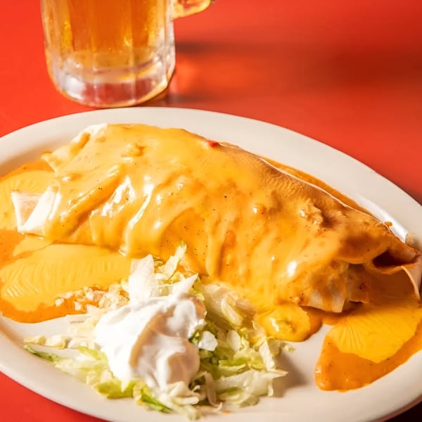 Julio's Mexican Restaurant's burrito smothered in cheese sauce, with shredded lettuce and sour cream.